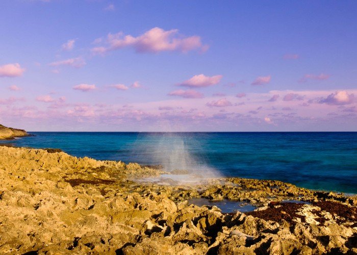 East End Cayman Islands shore with blowhole spraying water